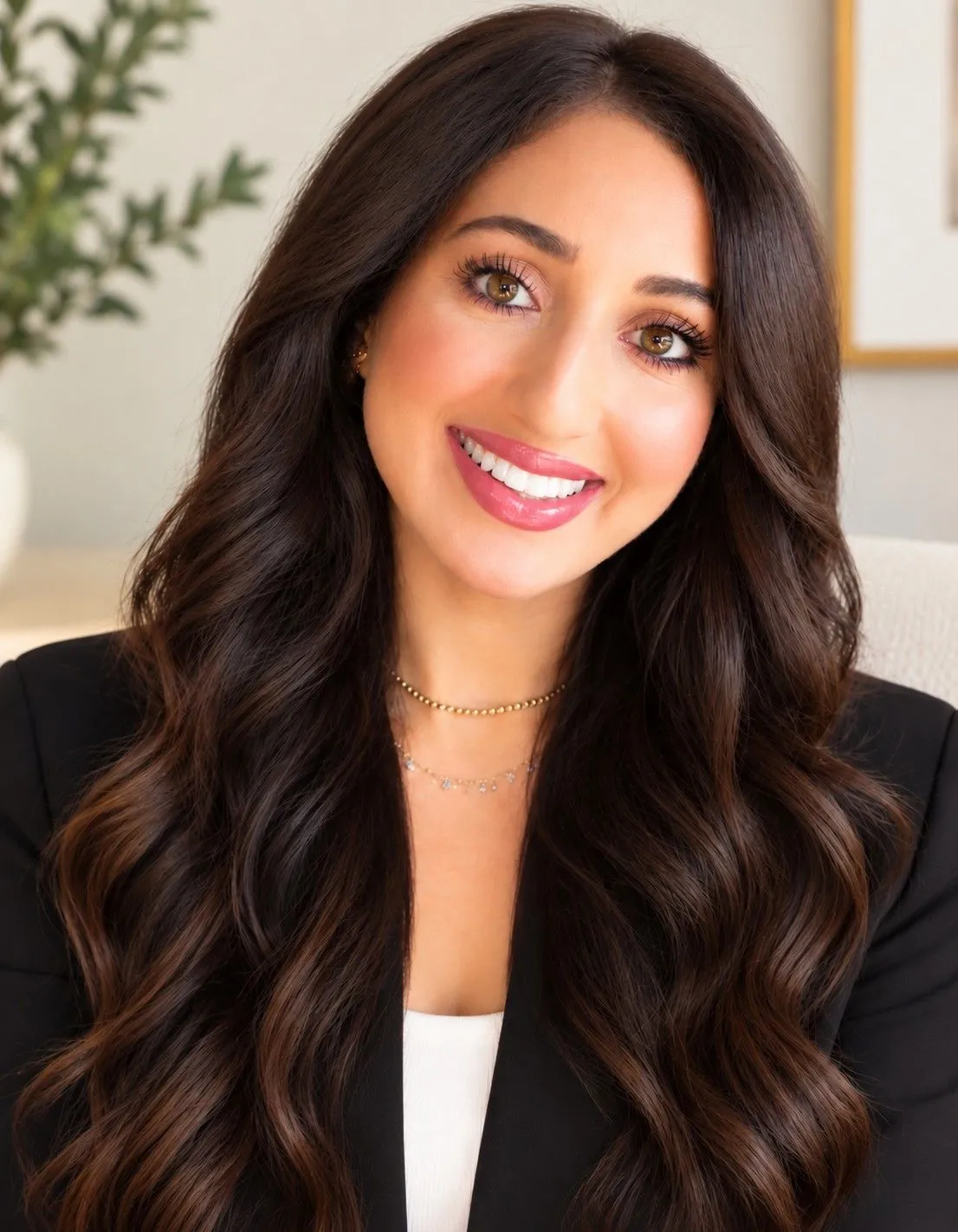 Portrait of Ranya Razooky, a therapist with long dark hair wearing a black blazer.