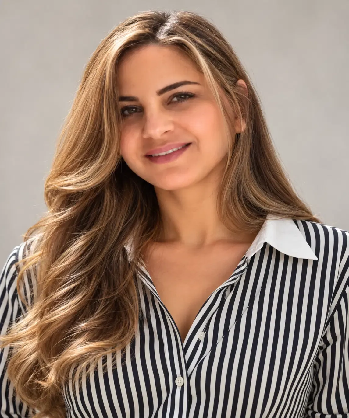 Portrait of Nadine Nasser, a woman with long brown hair wearing a black-and-white striped blouse.